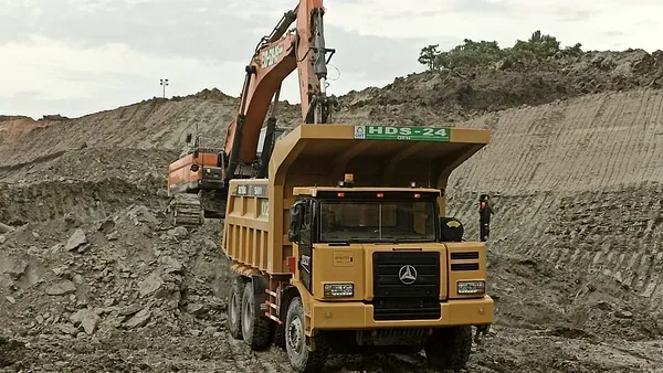 Rigid haul truck at a loading point with an excavator working the face behind it.