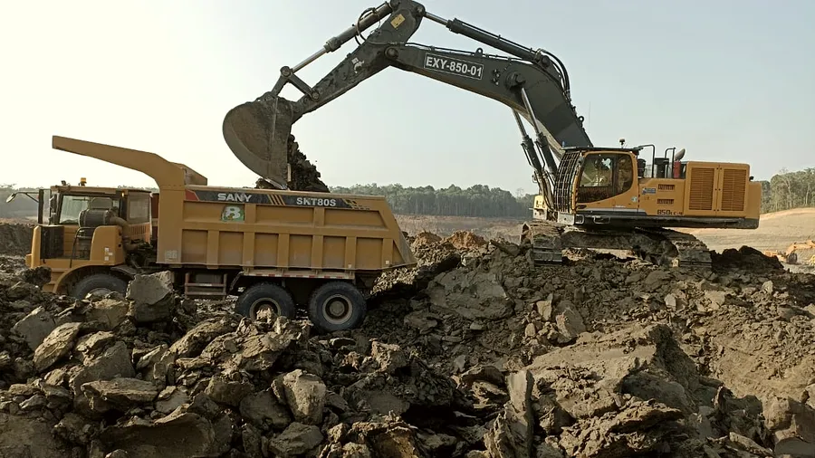 Excavator bucket swinging over the tray of a rigid haul truck at the loading point.
