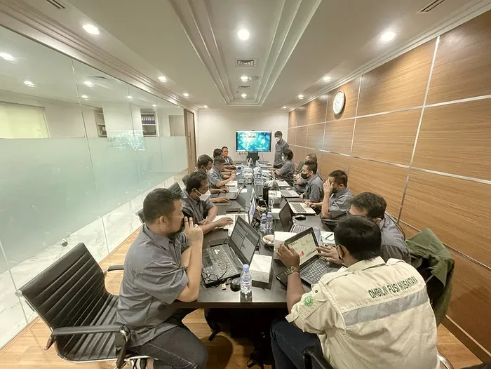 Operations team working through figures on laptops around a long table in the Jakarta office.