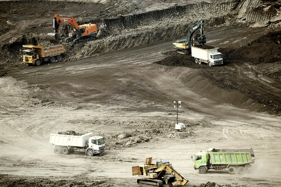 Wide view across a working pit with multiple excavators and haul trucks on the benches.