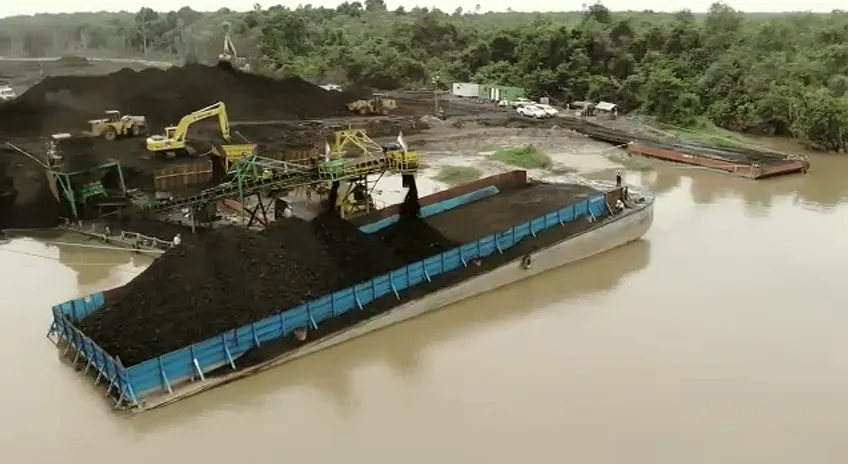 Aerial view of a river loading point with a barge being filled by conveyor alongside the bank.