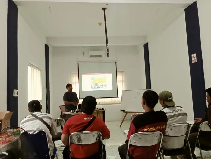 Site personnel seated for a briefing session in a training room, presenter at the screen.